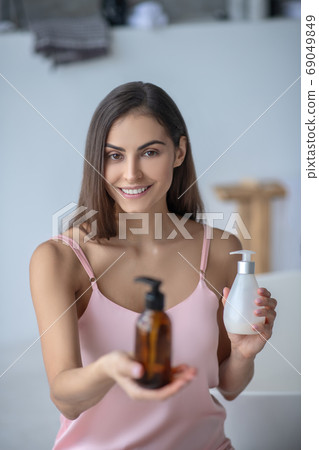Pretty long-haired woman holding beauty products 69049849