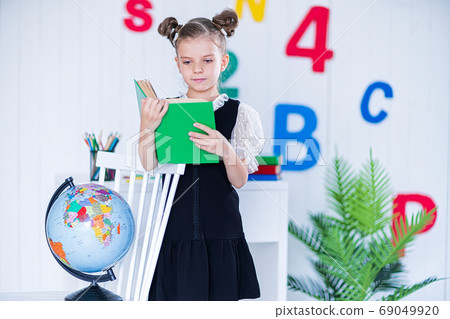 Happy smart girl in school unifrom hold book and look at camera Happy smart girl in school unifrom hold book and look at camera 69049920