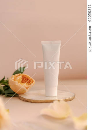 White cosmetic tube on light peach table 69050831
