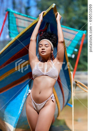 Model in bikini posing with old fishing boat Model in bikini posing with old fishing boat 69051099