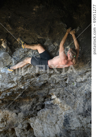 Young male climber bouldering a rock wall in a cave 69051277