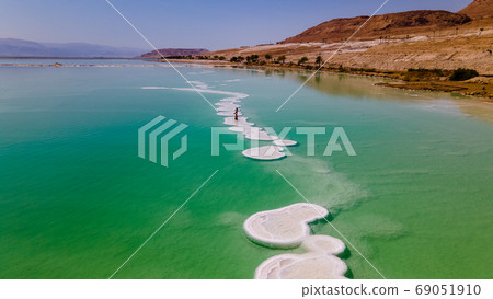 loving couple is resting on the dead sea. Salt coastline, The sea in Israel dies out and dries up loving couple is resting on the dead sea. Salt coastline, The sea in Israel dies out and dries up 69051910