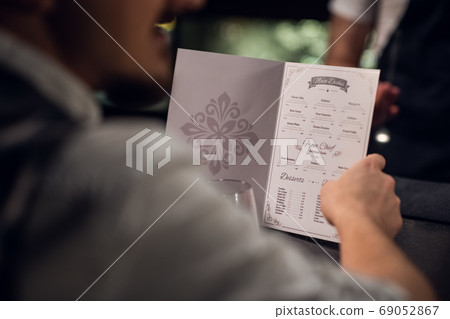 a man reads the menu in the bar, close-up of the menu and hands 69052867