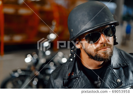 Portrait of bearded man motocyclist in dark sunglasses on dark background 69053958