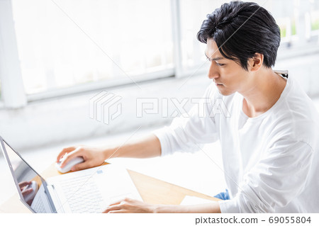 A young man looking at a computer screen with a serious look 69055804