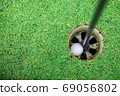 the golf ball in the golf hole. 69056802