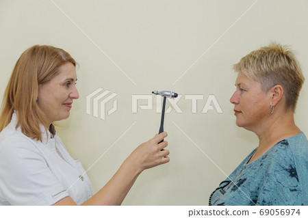 Woman neurologist examines a patient with a hammer 69056974
