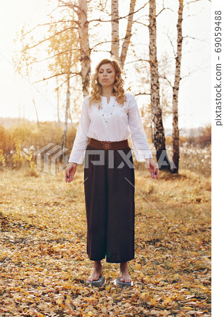 a woman meditates on needles in the autumn forest. spiritual practices on the nails. postures of yoga 69059488