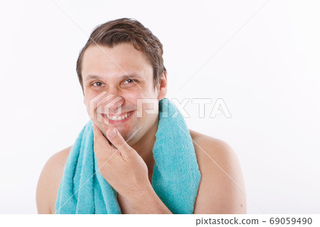 a man puts aftershave on his face. the guy strokes his face. morning treatments in the bathroom. copy space a man puts aftershave on his face. the guy strokes his face. morning treatments in the bathroom. copy space 69059490
