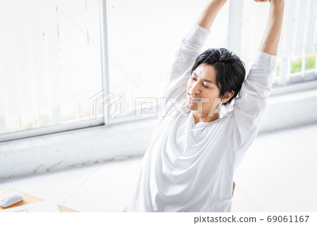 Young man stretching himself during desk work 69061167
