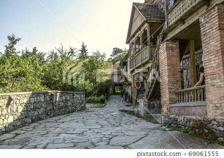 Narrow alley with old houses made of rough stone and brick columns,with wooden carved balconies in the Museum Tufenkian Old Dilijan Narrow alley with old houses made of rough stone and brick columns,with wooden carved balconies in the Museum Tufenkian Old Dilijan 69061555