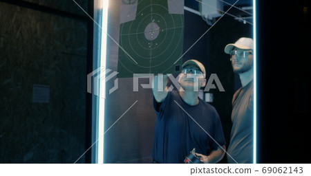 Male shooters examining target together 69062143