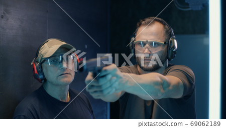 Mature instructor teaching man to shoot pistol 69062189
