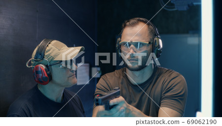 Mature instructor teaching man to shoot pistol 69062190