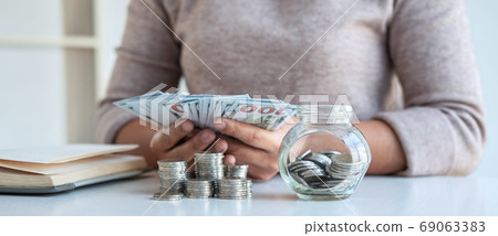 Young woman putting money into money box planning 69063383