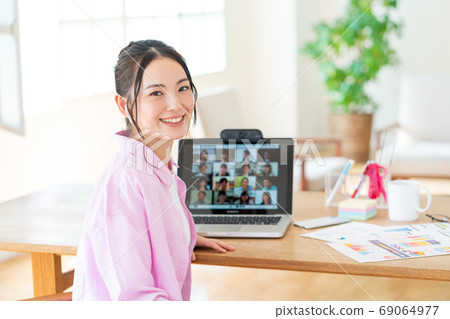Smiling young woman turning around with screen during telework web conference 69064977