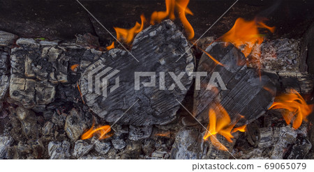 Hot coals and burning woods in the form of human heart. Glowing charcoal, bright red fire and ash. Hot coals and burning woods in the form of human heart. Glowing charcoal, bright red fire and ash. 69065079