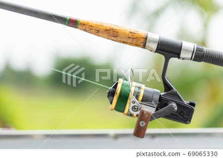 Fishing reel and rod in fisherman hand in a pond 69065330