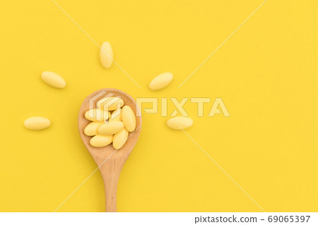 Yellow medicine in wooden spoon on yellow background 69065397