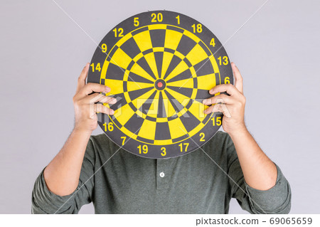 People holding yellow Dartboard and hide his face. Studio shot i 69065659