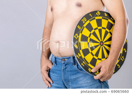 Fat people holding round yellow dartboard beside his belly posit Fat people holding round yellow dartboard beside his belly posit 69065660