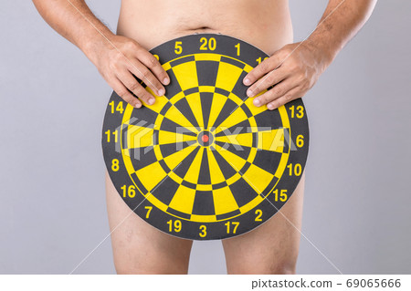 Man holding round yellow Dartboard to hide his penis position. S 69065666