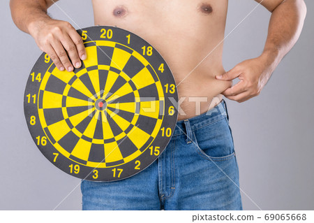 Fat people holding round yellow dartboard beside his belly posit Fat people holding round yellow dartboard beside his belly posit 69065668