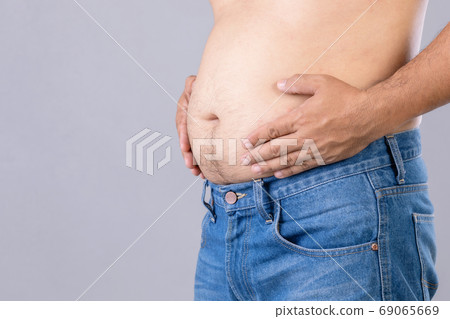 Fat man standing and show his tummy studio shot on grey backgrou Fat man standing and show his tummy studio shot on grey backgrou 69065669