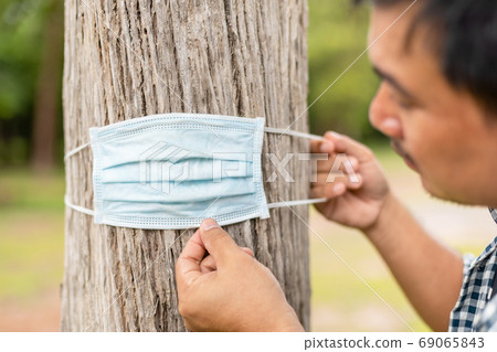 Man wearing protective mask for the tree. Take care the earth, L 69065843