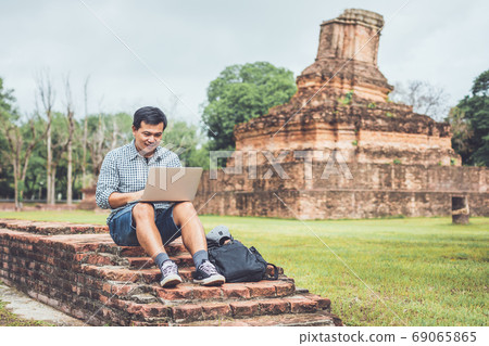Tourist working and using laptop at Sukhothai historical park, T Tourist working and using laptop at Sukhothai historical park, T 69065865