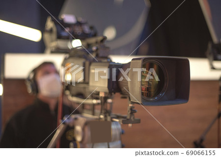 masked cameraman is filming a television show in the studio masked cameraman is filming a television show in the studio 69066155