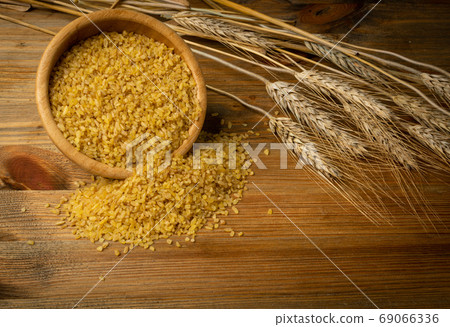 Bulgur Heap Scattered from Wooden Bowl on Wood Background 69066336