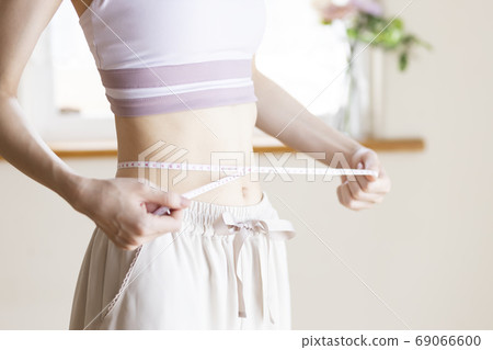 A woman measuring the waist A woman measuring the waist 69066600