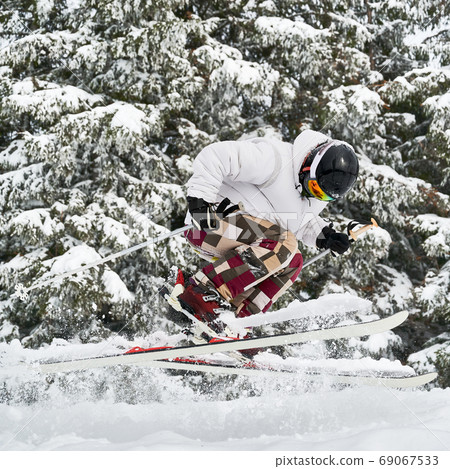 Young man on skis doing tricks with ski poles. 69067533