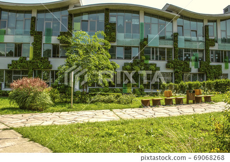 Facade of the academic buildings of The international College, covered  hanging gardens    of climbing plants in the suburbs of Dilijan 69068268