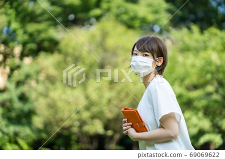 一個年輕的女人,走路與新的電暈肺炎手冊 一個年輕的女人,走路與新的電暈肺炎手冊 69069622