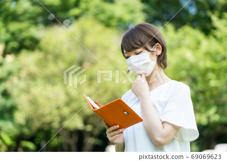 A young woman walking with the handbook of new corona pneumonia A young woman walking with the handbook of new corona pneumonia 69069623