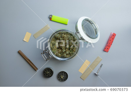 Top view of cannabis smoking stuff. Marijuana and paper on gray background Top view of cannabis smoking stuff. Marijuana and paper on gray background 69070373