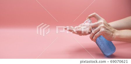 Woman hands using wash hand sanitizer gel pump dispenser. Clear 69070621