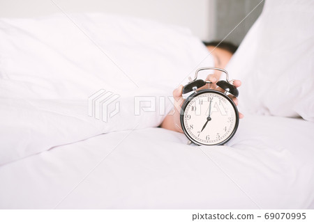 Woman sleep on the bed turns off the alarm clock wake up at the morning, Selective focus.. Woman sleep on the bed turns off the alarm clock wake up at the morning, Selective focus.. 69070995