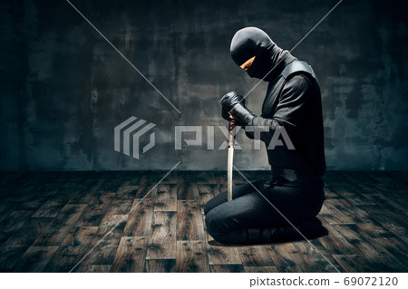 Warrior man sitting on floor posing with a sword 69072120