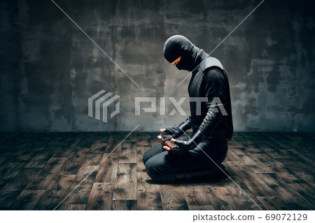 Warrior man sitting on floor posing with a sword 69072129
