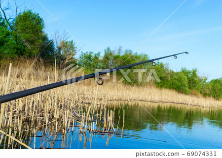 Fishing rod on the boat. A fishing rod is a long, flexible rod used by fishermen to catch fish. Fishing in the summer Fishing rod on the boat. A fishing rod is a long, flexible rod used by fishermen to catch fish. Fishing in the summer 69074331