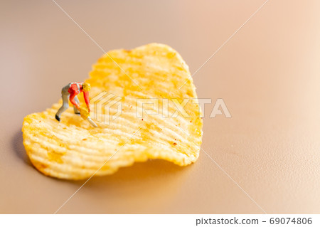 Miniature people Worker are working with potato chips Miniature people Worker are working with potato chips 69074806