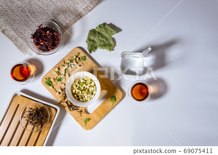 Chinese tea party. Dry granules of different types of tea. Flatlay, top view. herbal tea, on a white background Chinese tea party. Dry granules of different types of tea. Flatlay, top view. herbal tea, on a white background 69075411