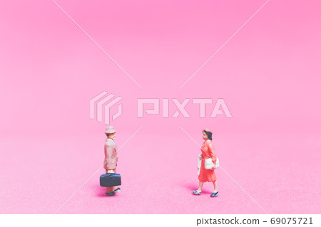Miniature people Couple of travellers on pink background Miniature people Couple of travellers on pink background 69075721