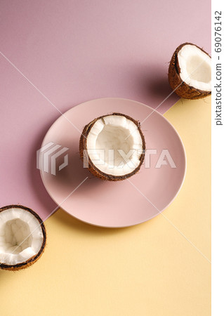 Coconut half in plate with nut fruits on cream yellow and pink Coconut half in plate with nut fruits on cream yellow and pink 69076142