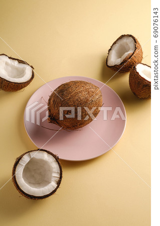 Coconut in pink plate with nut fruits on cream yellow 69076143