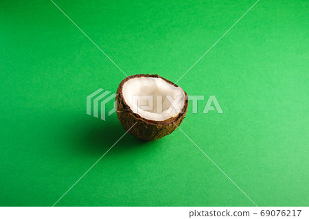 Single coconut fruit on green plain background 69076217