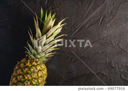 Fresh sweet pineapple on dark black textured background top vie Fresh sweet pineapple on dark black textured background top vie 69077916